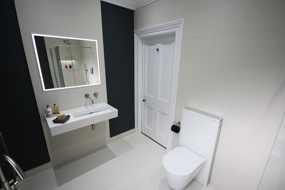 Photo of a medium sized contemporary family bathroom in Surrey with a freestanding bath, a walk-in shower, a wall mounted toilet, white tiles, porcelain tiles, blue walls, porcelain flooring, a wall-mounted sink and white floors.