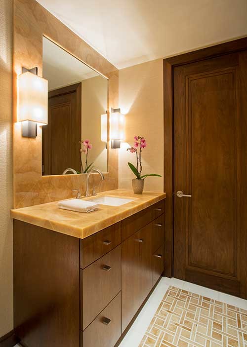 Exemple d'une salle d'eau tendance en bois foncé de taille moyenne avec un lavabo encastré, un placard à porte plane, un plan de toilette en onyx, une douche à l'italienne, WC suspendus, un mur beige et un sol en marbre.