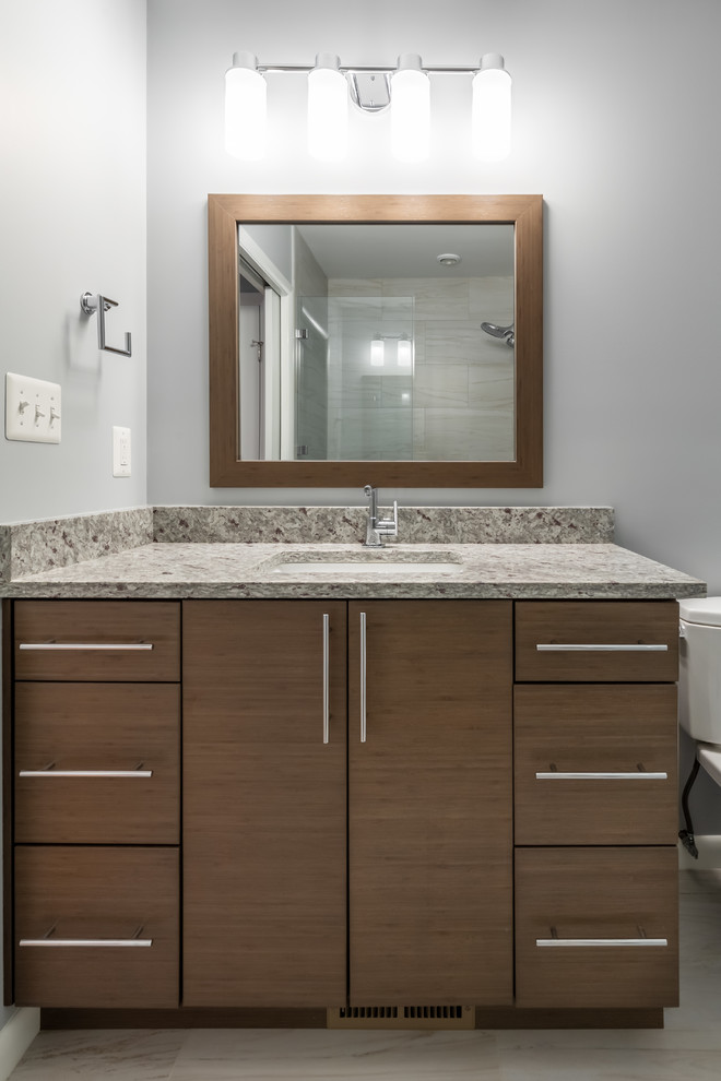 Photo of a medium sized traditional ensuite bathroom in DC Metro with flat-panel cabinets, brown cabinets, a two-piece toilet, grey walls, a submerged sink, engineered stone worktops, multi-coloured worktops, porcelain flooring and beige floors.