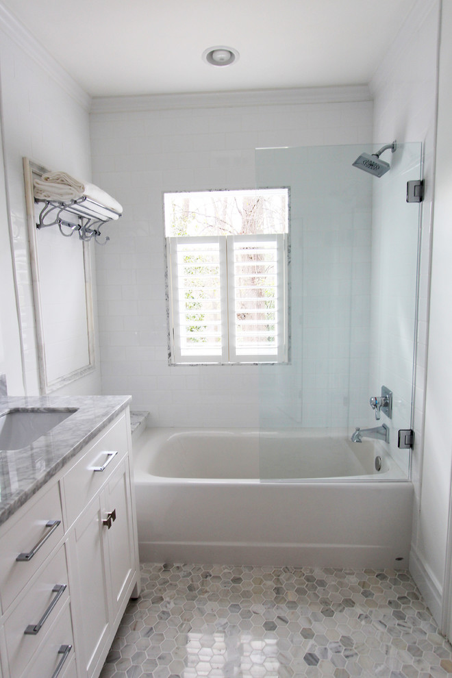Bild på ett litet vintage badrum, med ett undermonterad handfat, släta luckor, vita skåp, marmorbänkskiva, ett badkar i en alkov, en dusch/badkar-kombination, vit kakel, keramikplattor, vita väggar och marmorgolv