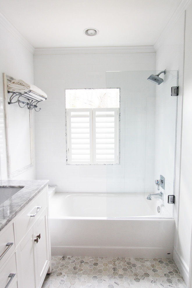 Foto på ett litet vintage badrum, med ett undermonterad handfat, släta luckor, vita skåp, marmorbänkskiva, ett badkar i en alkov, en dusch/badkar-kombination, en toalettstol med separat cisternkåpa, vit kakel, keramikplattor, vita väggar och marmorgolv