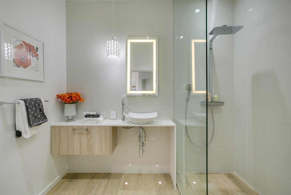 Свежая идея для дизайна: ванная комната среднего размера в стиле модернизм с плоскими фасадами, светлыми деревянными фасадами, открытым душем, белой плиткой, керамогранитной плиткой, белыми стенами, полом из керамогранита, душевой кабиной, настольной раковиной, столешницей из искусственного камня, бежевым полом и открытым душем - отличное фото интерьера