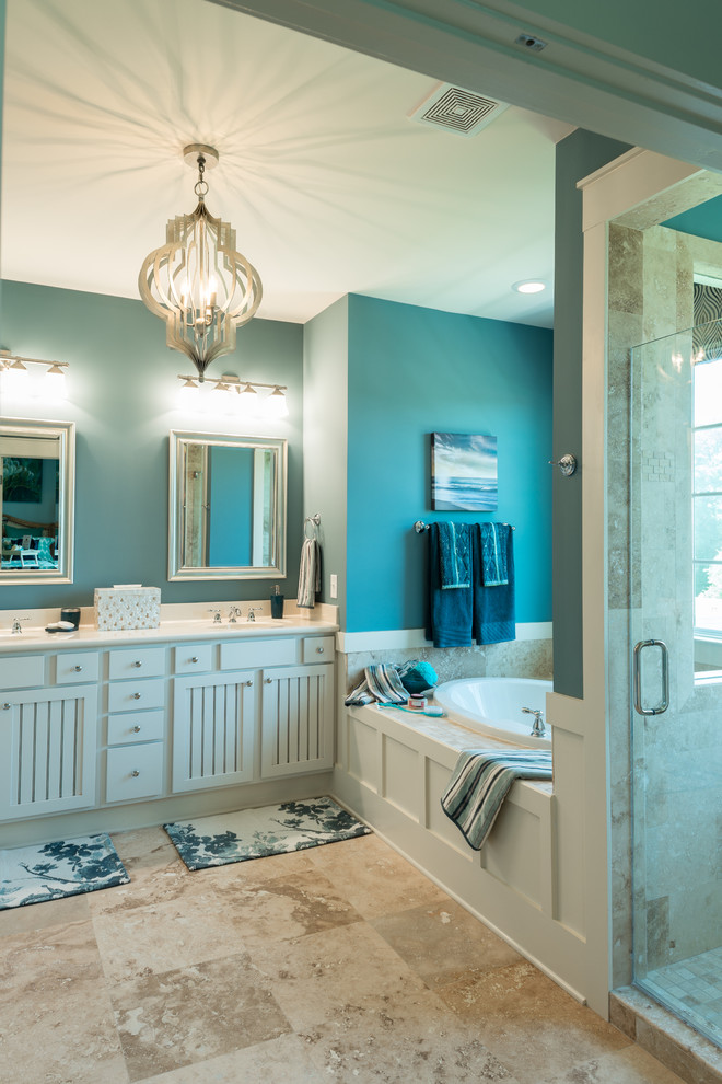 На фото: главная ванная комната среднего размера в морском стиле с фасадами с филенкой типа жалюзи, белыми фасадами, накладной ванной, душем в нише, бежевой плиткой, каменной плиткой, синими стенами, полом из травертина, бежевым полом и душем с распашными дверями с