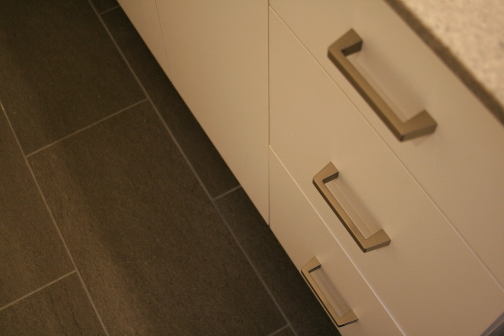 Exempel på ett modernt badrum, med släta luckor, vita skåp, beige väggar och grått golv