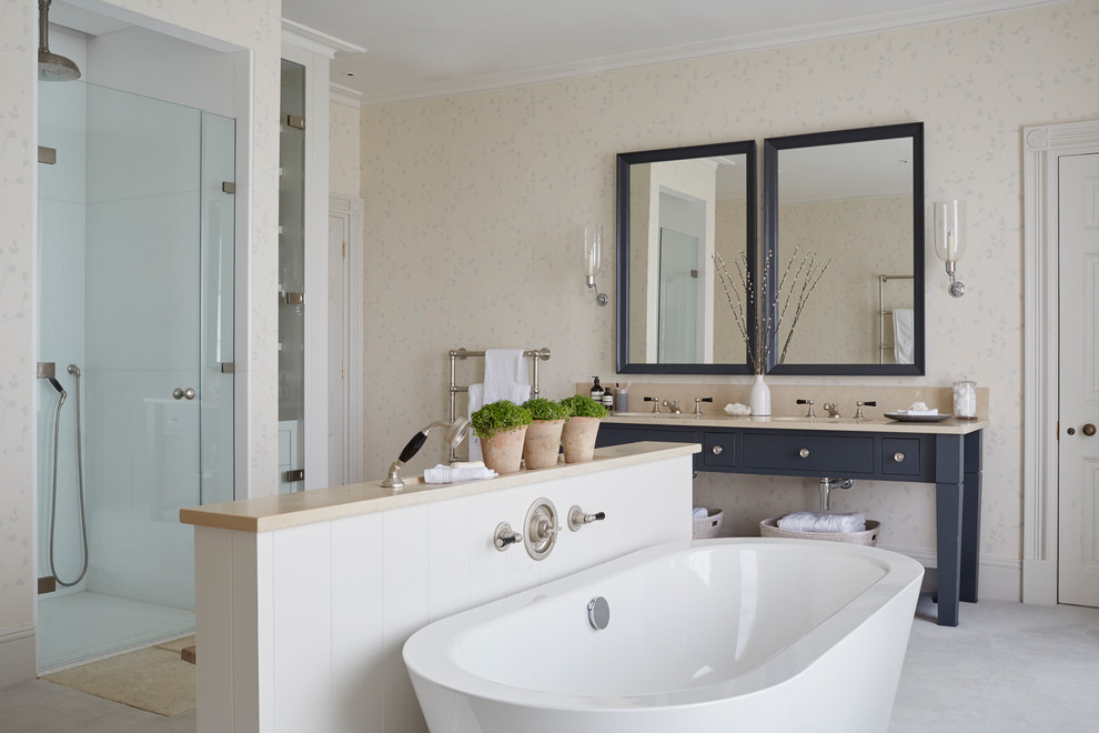 Photo of a classic ensuite bathroom with flat-panel cabinets, blue cabinets, a freestanding bath, an alcove shower, white tiles, beige walls, a submerged sink, grey floors, a hinged door and beige worktops.