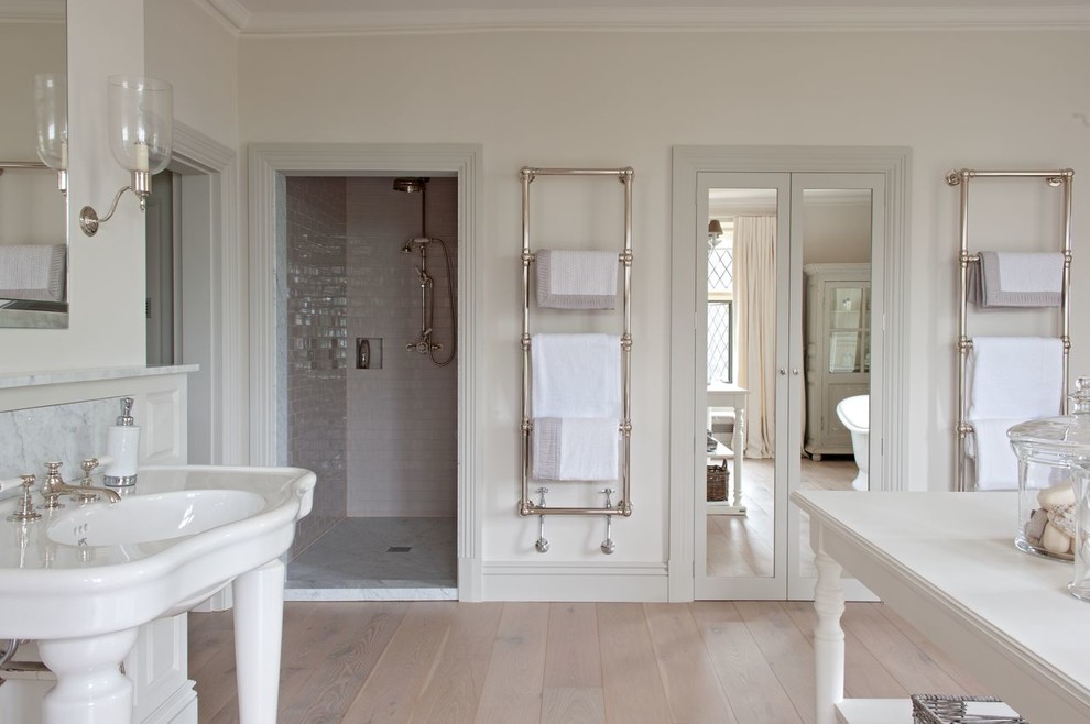 Esempio di una stanza da bagno padronale country con lavabo a colonna, vasca freestanding, doccia alcova, piastrelle bianche, piastrelle in ceramica, pareti bianche e parquet chiaro