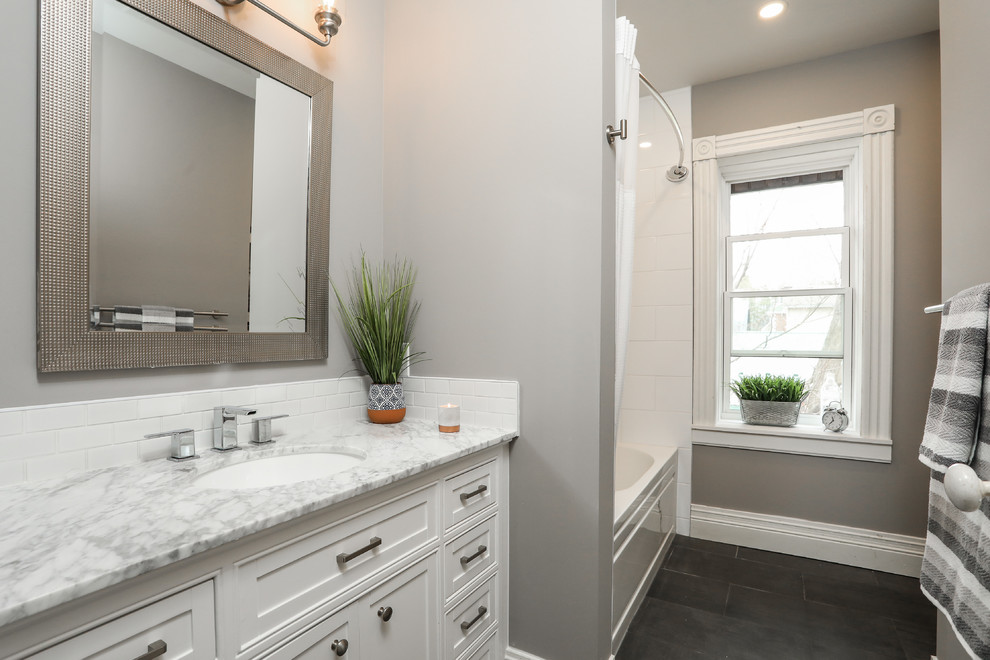 Aménagement d'une salle de bain classique de taille moyenne avec un placard à porte shaker, des portes de placard blanches, une baignoire en alcôve, un combiné douche/baignoire, WC à poser, un carrelage blanc, un mur gris, un lavabo encastré, un sol gris, une cabine de douche avec un rideau et un plan de toilette gris.