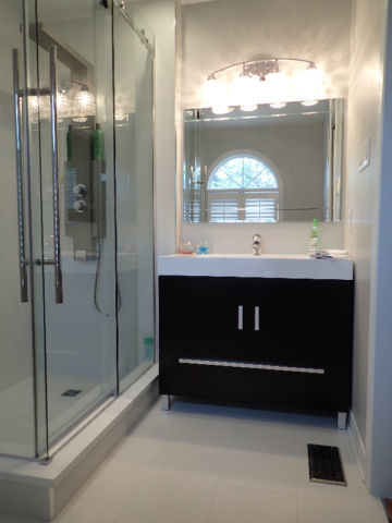 Bild på ett mellanstort vintage badrum med dusch, med släta luckor, svarta skåp, en dusch i en alkov, en toalettstol med hel cisternkåpa, vit kakel, porslinskakel, vita väggar, klinkergolv i porslin, ett undermonterad handfat och bänkskiva i akrylsten