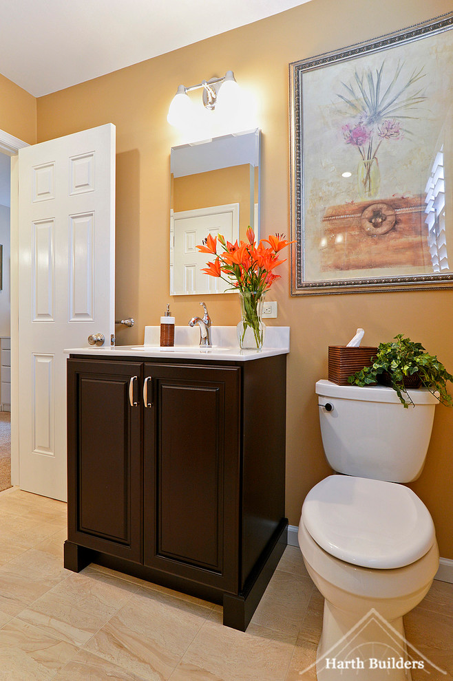 Esempio di una stanza da bagno chic con lavabo sottopiano, ante con bugna sagomata, ante marroni, top in marmo, WC a due pezzi, piastrelle beige, pareti arancioni e pavimento con piastrelle in ceramica