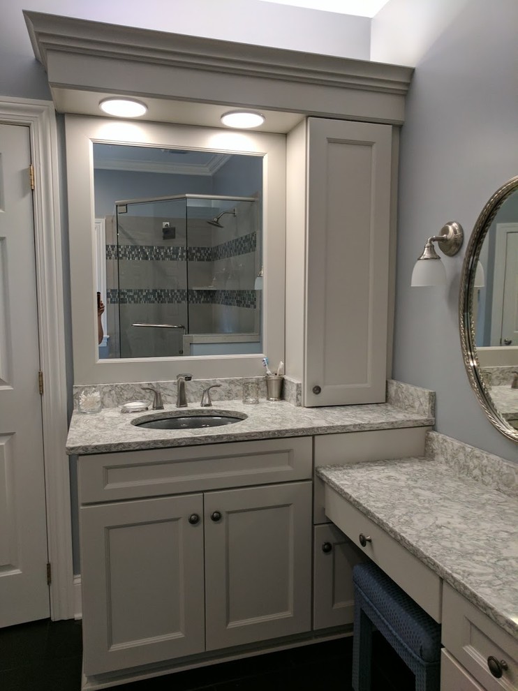 This is an example of a traditional bathroom in Charlotte with shaker cabinets, grey cabinets, a freestanding bath, a corner shower, grey tiles, stone tiles, porcelain flooring, a submerged sink, black floors and a hinged door.
