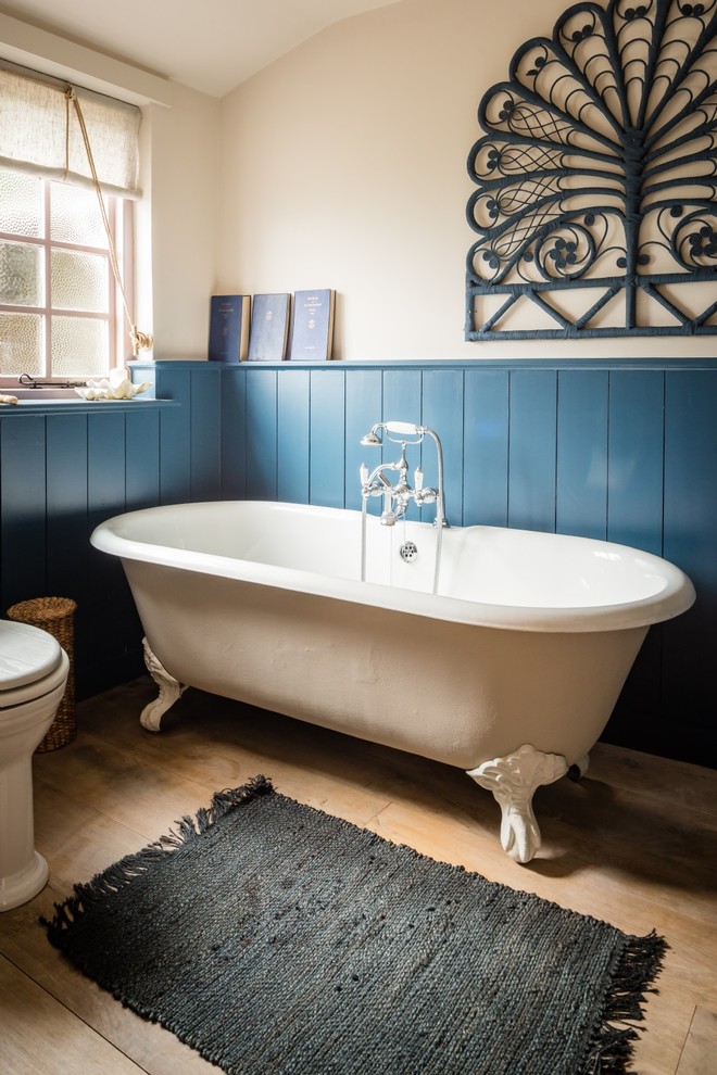 Photo of a medium sized mediterranean family bathroom in Cornwall with a claw-foot bath, a one-piece toilet, beige walls, light hardwood flooring and a console sink.