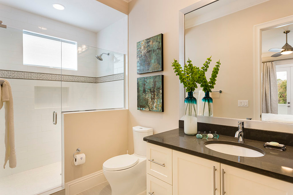 Example of a transitional 3/4 white tile and porcelain tile porcelain tile corner shower design in Orlando with shaker cabinets, a two-piece toilet, gray walls, a drop-in sink, quartz countertops and white cabinets