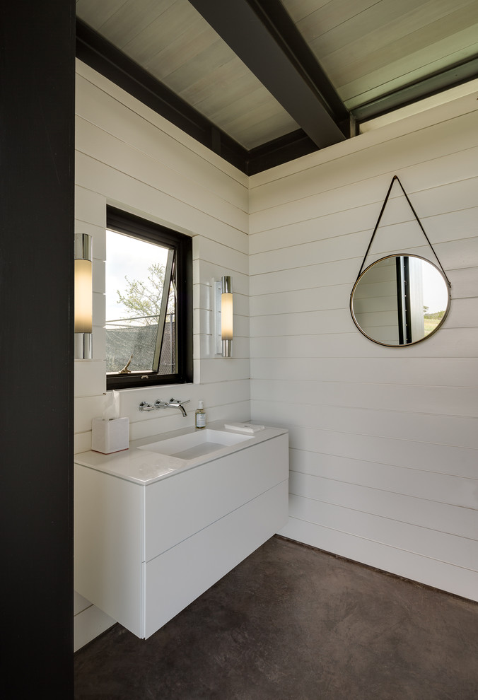 Kleines Modernes Badezimmer mit integriertem Waschbecken, verzierten Schränken, weißen Schränken, Mineralwerkstoff-Waschtisch, weißer Wandfarbe und Betonboden in Austin