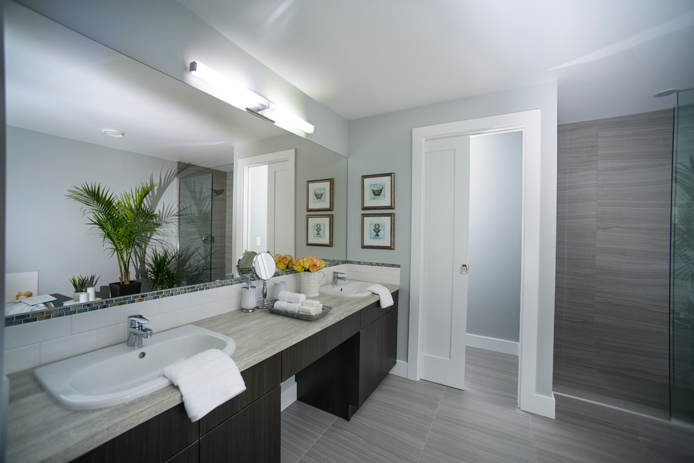Cette photo montre une salle de bain principale tendance en bois foncé avec un lavabo posé, un placard à porte plane, un plan de toilette en stratifié, une douche ouverte, un carrelage gris, des carreaux de porcelaine, un mur gris et un sol en carrelage de porcelaine.