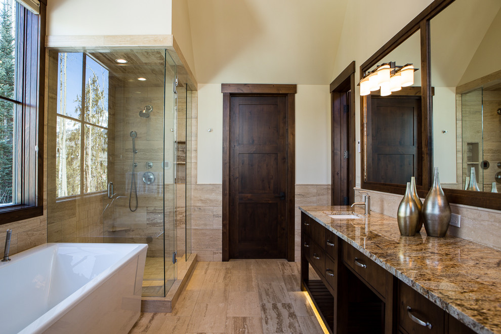 This is an example of a classic ensuite bathroom in Orange County with flat-panel cabinets, dark wood cabinets, a freestanding bath, a corner shower, beige tiles, beige walls, a submerged sink, beige floors, a hinged door and beige worktops.