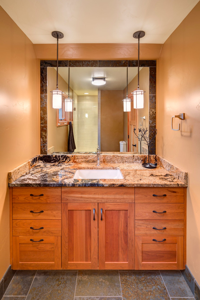 Amerikansk inredning av ett litet badrum med dusch, med skåp i shakerstil, skåp i mellenmörkt trä, en öppen dusch, en toalettstol med separat cisternkåpa, grå kakel, stenkakel, orange väggar, skiffergolv, ett undermonterad handfat och granitbänkskiva