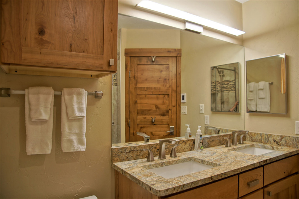 Example of a mid-sized mountain style 3/4 beige tile and glass tile porcelain tile and beige floor bathroom design in San Francisco with shaker cabinets, medium tone wood cabinets, a two-piece toilet, beige walls, an undermount sink and granite countertops
