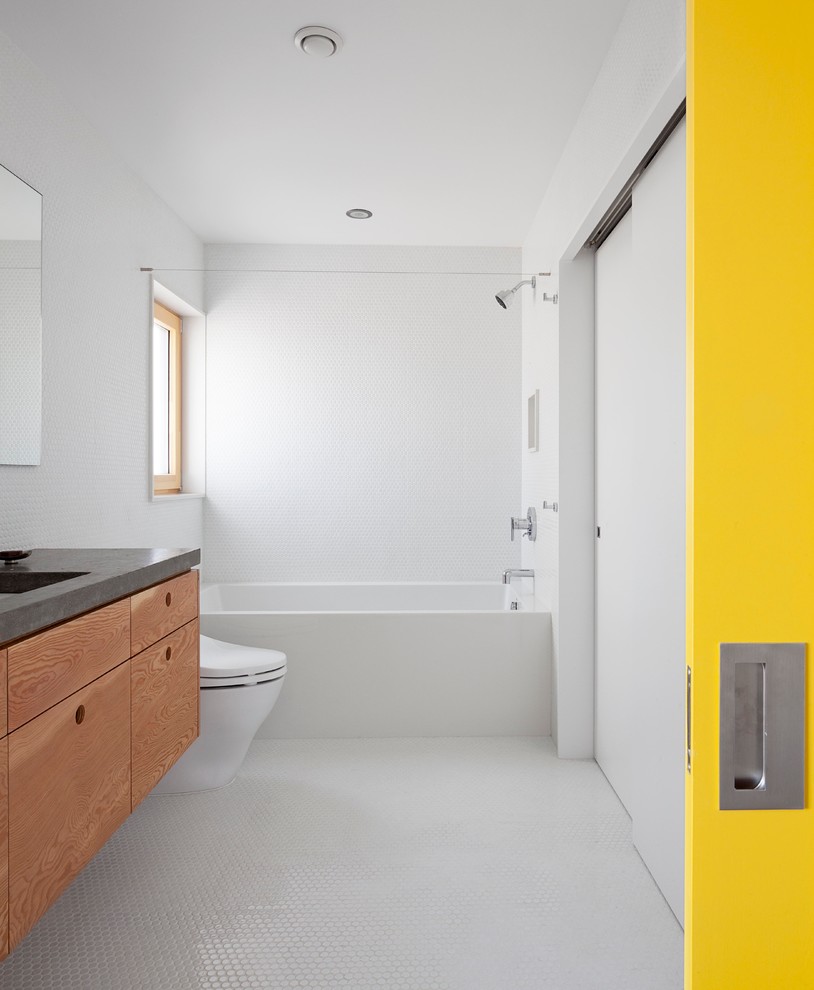 Modelo de cuarto de baño actual con puertas de armario de madera oscura, bañera empotrada, combinación de ducha y bañera, baldosas y/o azulejos blancos, paredes blancas y suelo con mosaicos de baldosas