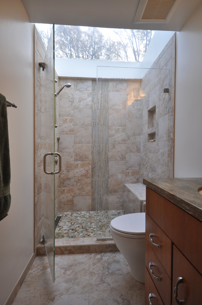 Photo of a large classic ensuite bathroom in DC Metro with flat-panel cabinets, medium wood cabinets, an alcove shower, a two-piece toilet, beige tiles, beige walls, ceramic flooring, a submerged sink and solid surface worktops.