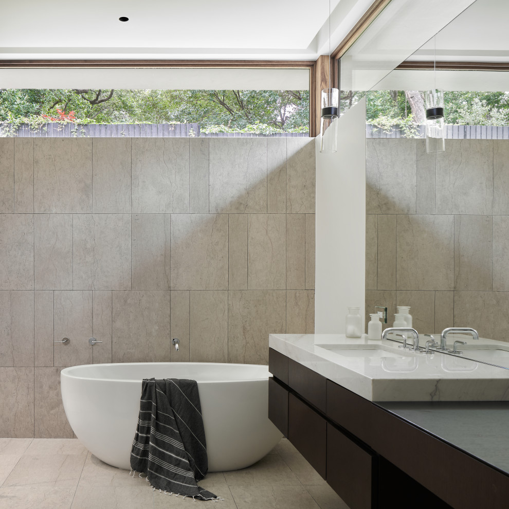 Modern bathroom in Austin with flat-panel cabinets, dark wood cabinets, a freestanding bath, grey tiles, white walls, a submerged sink, grey floors, grey worktops, a single sink and a floating vanity unit.