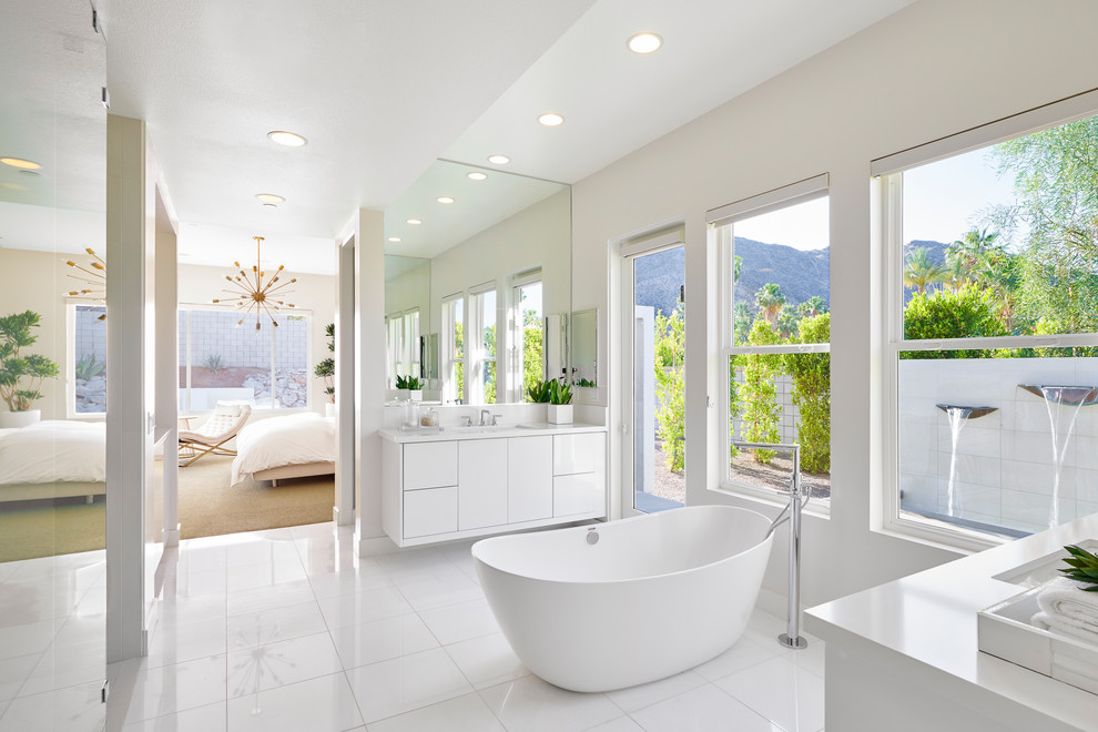 Пример оригинального дизайна: главная ванная комната в стиле ретро с плоскими фасадами, белыми фасадами, отдельно стоящей ванной, белыми стенами, врезной раковиной, белым полом и белой столешницей