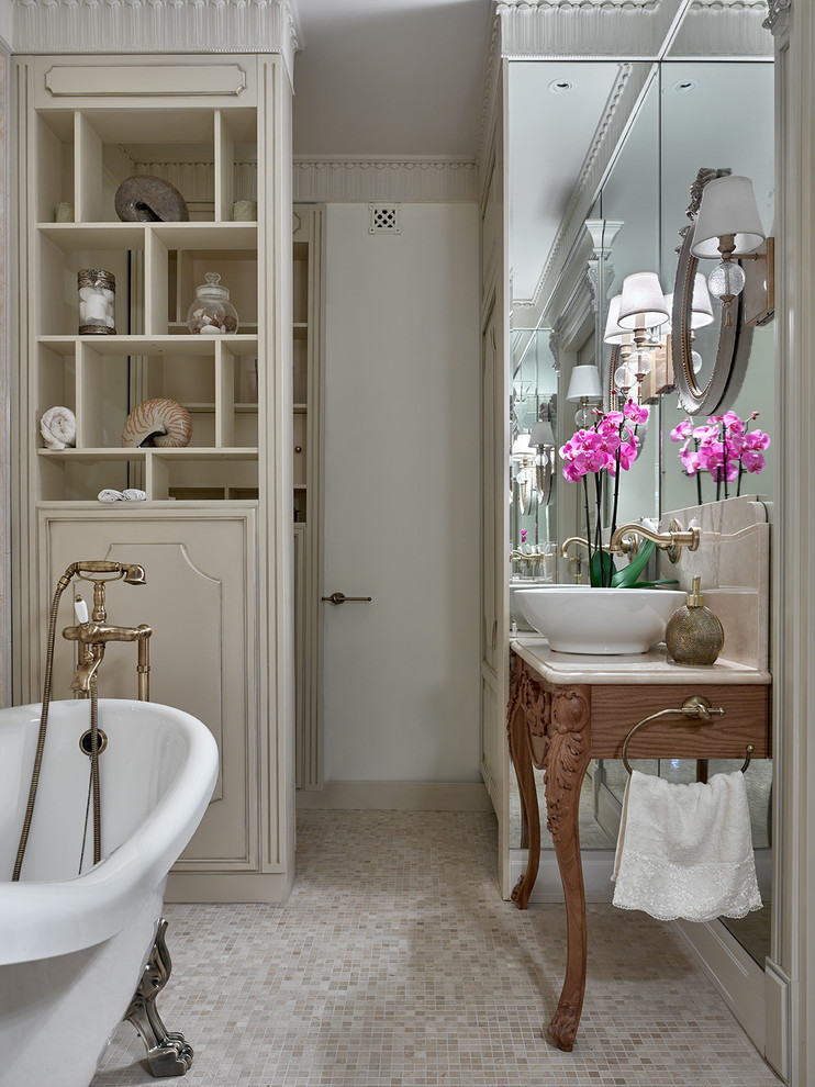 На фото: ванная комната в классическом стиле с ванной на ножках и настольной раковиной с