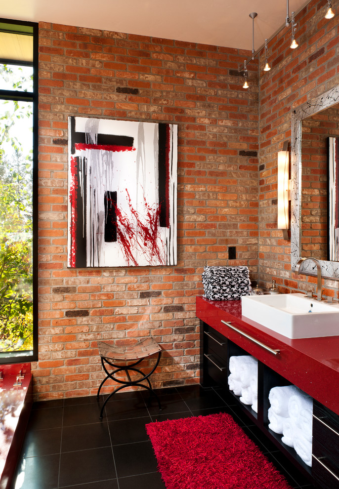 Cette photo montre une salle de bain tendance avec une vasque, des portes de placard noires, un plan de toilette rouge et un placard à porte plane.