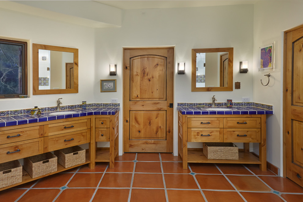 Пример оригинального дизайна: огромная ванная комната в стиле фьюжн с фасадами островного типа, светлыми деревянными фасадами, унитазом-моноблоком, синей плиткой, терракотовой плиткой, бежевыми стенами, полом из терракотовой плитки, врезной раковиной и столешницей из плитки