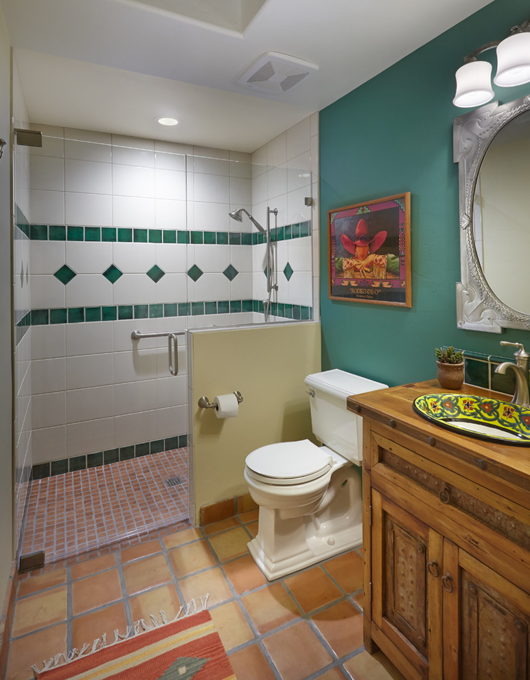 Inredning av ett amerikanskt mycket stort en-suite badrum, med möbel-liknande, skåp i ljust trä, en kantlös dusch, en toalettstol med hel cisternkåpa, perrakottakakel, gröna väggar, klinkergolv i terrakotta, ett nedsänkt handfat och träbänkskiva