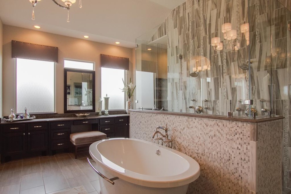 Inredning av ett modernt badrum, med ett fristående badkar, en kantlös dusch, grå kakel, marmorkakel, klinkergolv i porslin, granitbänkskiva, grått golv och med dusch som är öppen