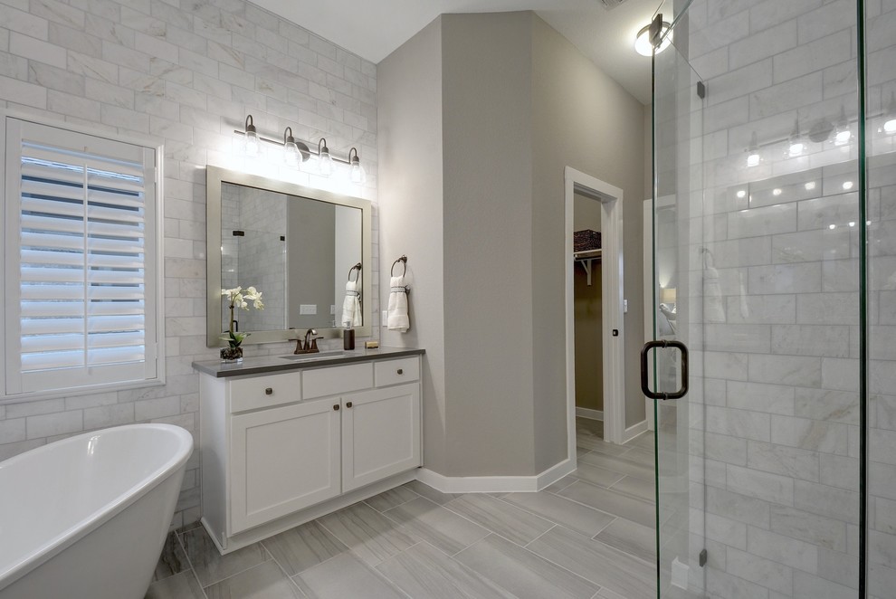 Cette image montre une salle de bain principale traditionnelle avec un placard à porte shaker, des portes de placard blanches, une baignoire indépendante, une douche d'angle, un carrelage gris, un mur gris, parquet peint, un lavabo encastré, un sol gris, une cabine de douche à porte battante et un plan de toilette gris.