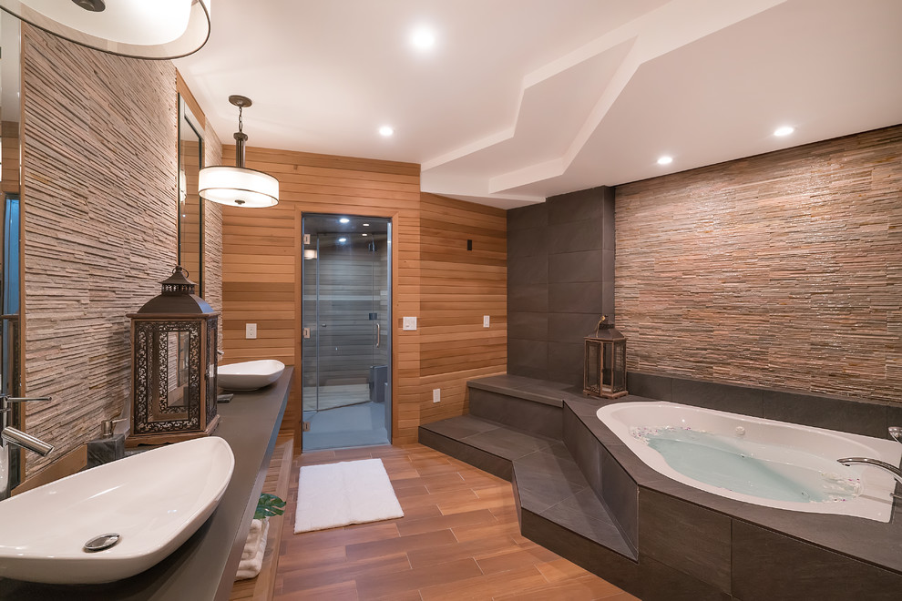 На фото: главная ванная комната в восточном стиле с гидромассажной ванной, коричневыми стенами, настольной раковиной и коричневым полом с