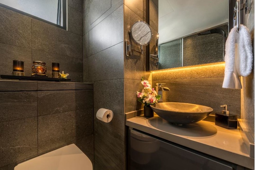 Cette image montre une petite douche en alcôve design avec WC à poser, un carrelage gris et une vasque.