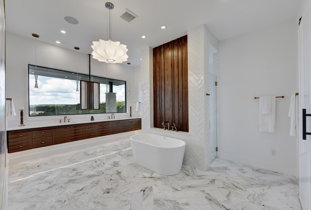Cette image montre une très grande salle de bain principale design en bois foncé avec un placard à porte plane, une baignoire indépendante, une douche double, un carrelage blanc, des carreaux de porcelaine, un mur blanc, un sol en marbre, un lavabo encastré, un plan de toilette en marbre, un sol gris, une cabine de douche à porte battante et un plan de toilette blanc.