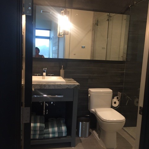 Foto på ett litet funkis badrum med dusch, med öppna hyllor, blå skåp, en dusch i en alkov, grå kakel, skifferkakel, grå väggar, cementgolv och dusch med skjutdörr