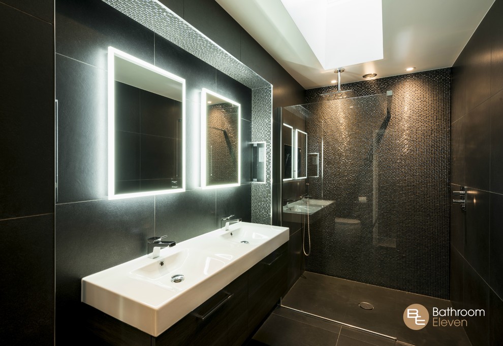 This is an example of a contemporary ensuite bathroom with a walk-in shower, black tiles, mosaic tiles, black walls, ceramic flooring, an integrated sink and brown cabinets.