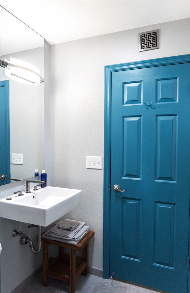 Foto på ett litet funkis badrum, med en öppen dusch, en toalettstol med separat cisternkåpa, grå kakel, travertinkakel, grå väggar, travertin golv, ett väggmonterat handfat och grått golv