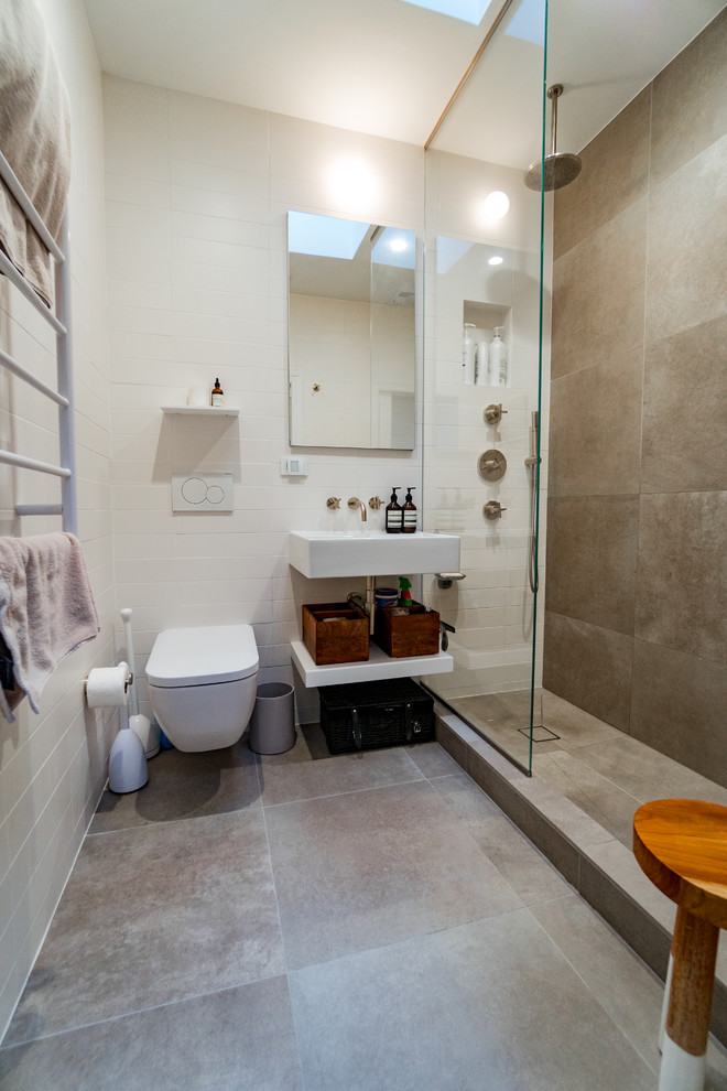 Idéer för små funkis badrum med dusch, med en dusch i en alkov, en vägghängd toalettstol, vit kakel, tunnelbanekakel, vita väggar, klinkergolv i keramik, ett väggmonterat handfat, grått golv och med dusch som är öppen