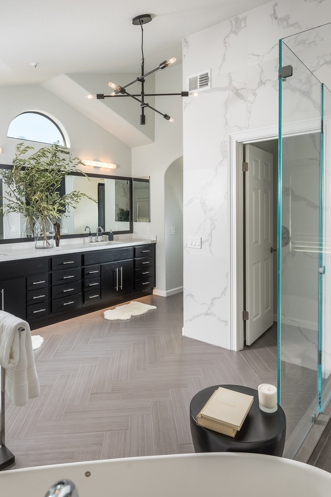 Inredning av ett modernt stort vit vitt en-suite badrum, med släta luckor, svarta skåp, ett fristående badkar, en hörndusch, grå kakel, porslinskakel, grå väggar, klinkergolv i porslin, ett undermonterad handfat, bänkskiva i kvarts, grått golv och dusch med gångjärnsdörr