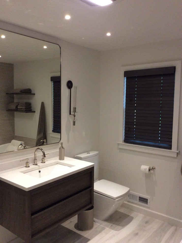 This is an example of a large modern ensuite bathroom in New York with flat-panel cabinets, dark wood cabinets, a built-in bath, a corner shower, a two-piece toilet, beige tiles, cement tiles, beige walls, ceramic flooring, a built-in sink, solid surface worktops, grey floors and a hinged door.