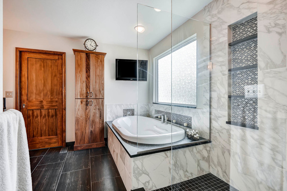 Expansive traditional ensuite bathroom in Denver with a vessel sink, flat-panel cabinets, medium wood cabinets, engineered stone worktops, a built-in bath, a corner shower, a two-piece toilet, black tiles, stone tiles, white walls and porcelain flooring.