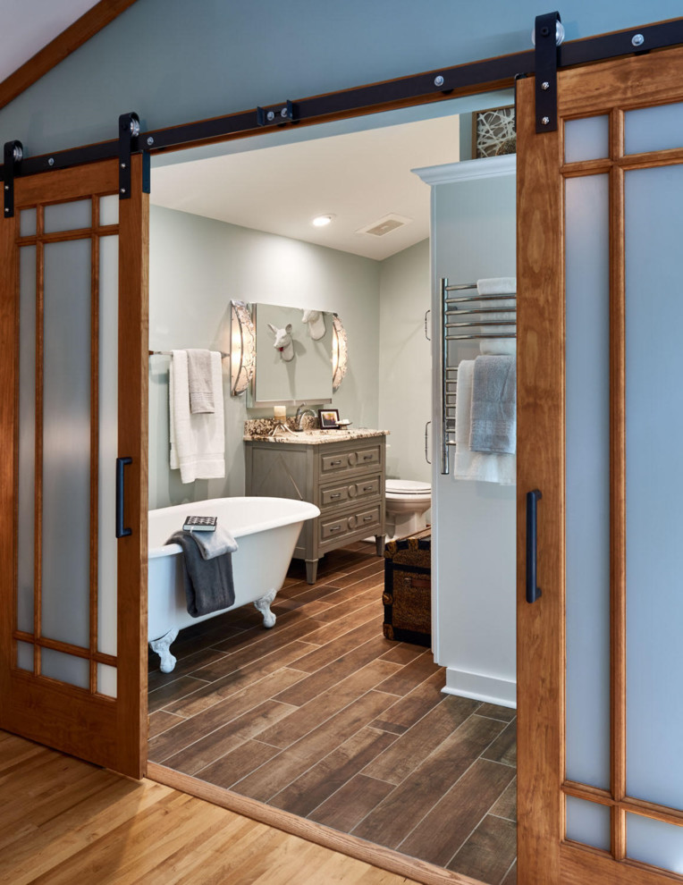 На фото: главная ванная комната в стиле фьюжн с фасадами островного типа, серыми фасадами, ванной на ножках, душем в нише, полом из керамогранита и столешницей из гранита с