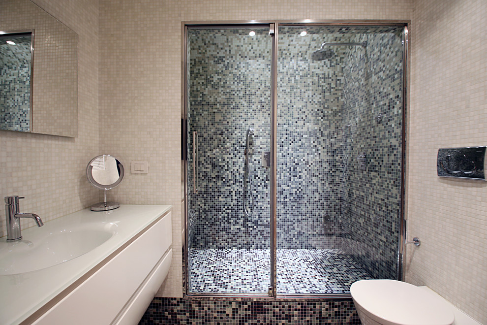 Esempio di una piccola stanza da bagno con doccia design con lavabo integrato, ante lisce, ante bianche, top in vetro, doccia alcova, WC a due pezzi, piastrelle grigie, piastrelle a mosaico, pareti bianche e pavimento con piastrelle a mosaico