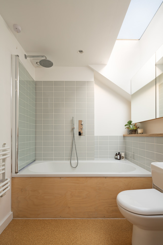 Mittelgroßes Nordisches Badezimmer En Suite mit Einbaubadewanne, Wandtoilette mit Spülkasten, weißer Wandfarbe, Duschbadewanne, grauen Fliesen und Korkboden in London