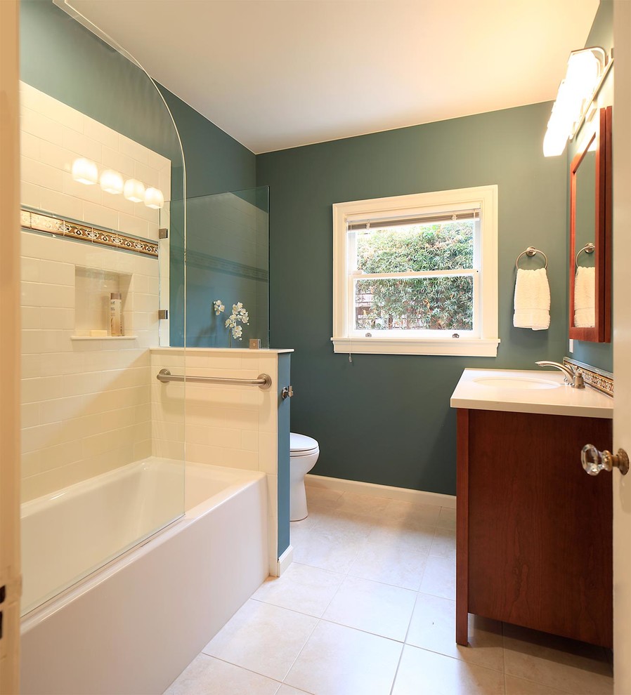 Exempel på ett litet medelhavsstil en-suite badrum, med ett undermonterad handfat, möbel-liknande, skåp i mellenmörkt trä, bänkskiva i akrylsten, ett badkar i en alkov, en dusch/badkar-kombination, en toalettstol med separat cisternkåpa, beige kakel, keramikplattor, gröna väggar och klinkergolv i keramik