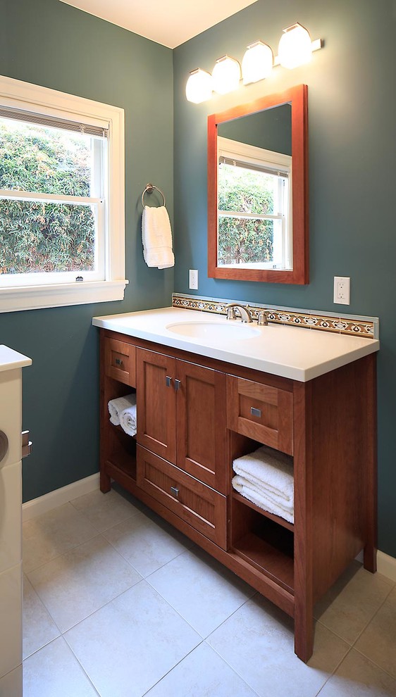 This is an example of a small mediterranean ensuite bathroom in San Francisco with a submerged sink, freestanding cabinets, medium wood cabinets, solid surface worktops, an alcove bath, a shower/bath combination, a two-piece toilet, beige tiles, ceramic tiles, green walls and ceramic flooring.