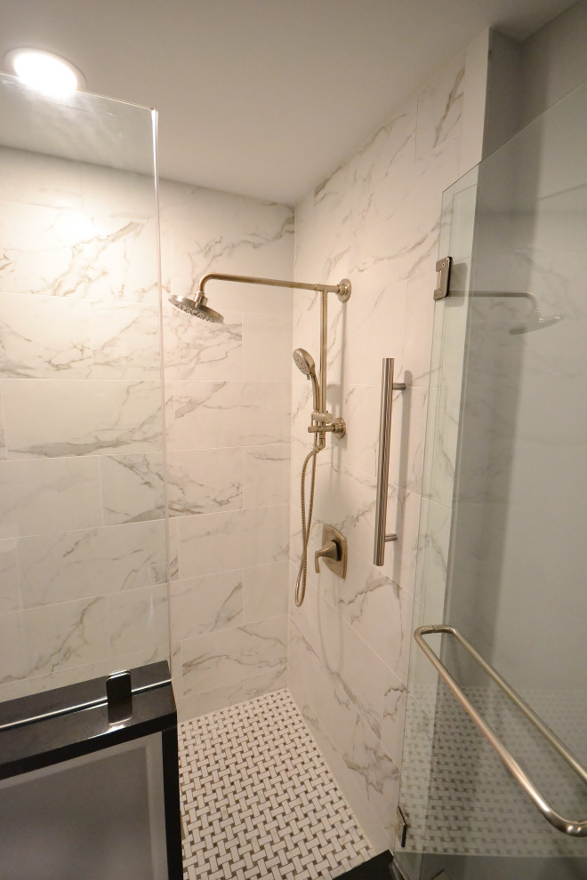 Medium sized classic ensuite bathroom in Philadelphia with raised-panel cabinets, white cabinets, a corner shower, a one-piece toilet, white tiles, marble tiles, grey walls, laminate floors, a submerged sink, granite worktops, grey floors, a hinged door and black worktops.