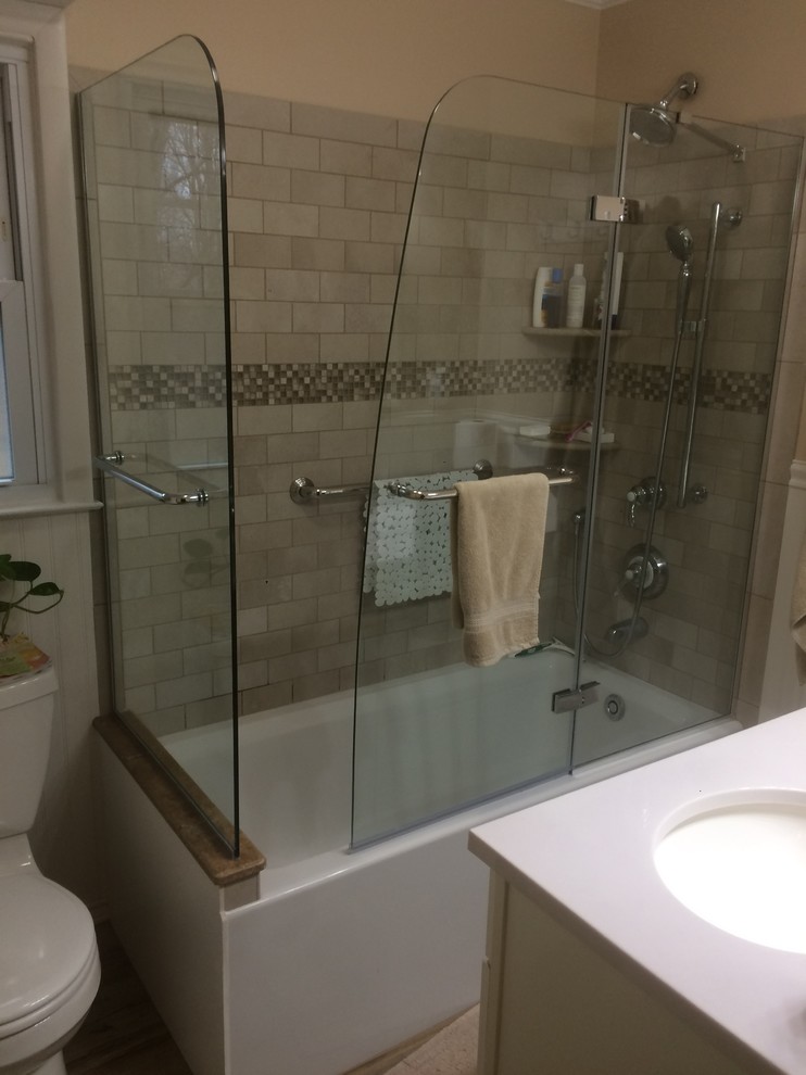 На фото: маленькая ванная комната в стиле кантри с белыми фасадами, угловой ванной, душем над ванной, раздельным унитазом, бежевой плиткой, коричневой плиткой, каменной плиткой, бежевыми стенами, полом из керамической плитки, душевой кабиной, подвесной раковиной, столешницей из искусственного камня, бежевым полом и душем с распашными дверями для на участке и в саду