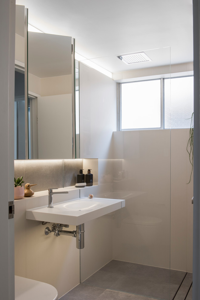 Inspiration för ett litet funkis en-suite badrum, med en öppen dusch, en vägghängd toalettstol, beige kakel, cementkakel, vita väggar, cementgolv, ett väggmonterat handfat, bänkskiva i akrylsten, grått golv och med dusch som är öppen