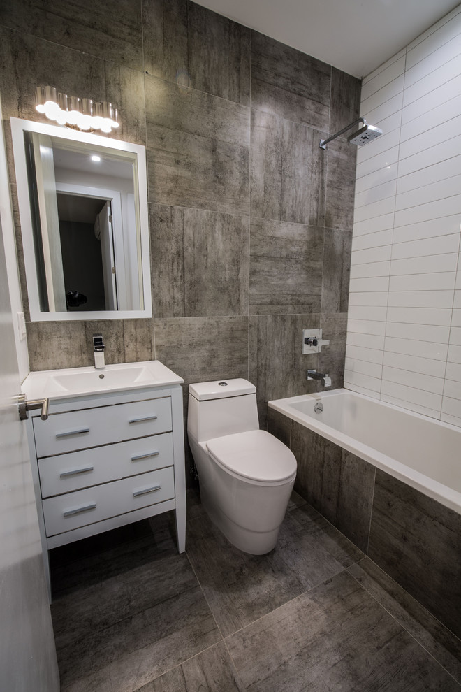 Aménagement d'une petite salle de bain contemporaine avec un lavabo intégré, un combiné douche/baignoire, WC à poser, un carrelage blanc, un placard à porte plane, des portes de placard blanches et une baignoire posée.